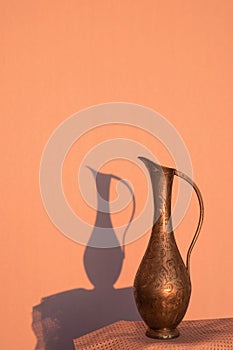 Old copper jug and its dark shadow