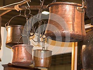 Old copper pots hanged on iron hooks