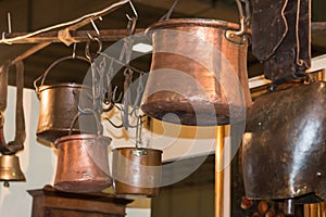 Old copper pots hanged on iron hooks