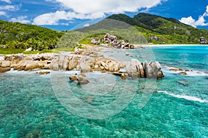 Old coral reef in the white sand beach on secluded beach of grand anse, La Digue, Seychelles. Aerial view photo