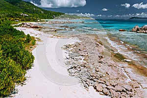Old coral reef in the white sand beach on secluded beach of grand anse, La Digue, Seychelles. Aerial view photo