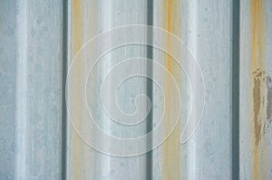 An old metal rippled wall with rusty streams. Abstract background.