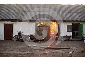 An old country courtyard where chickens walk and a retro motorcycle stands