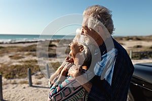 Old couple with a car at the beach