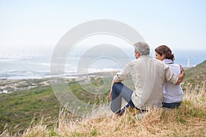 Old couple, hug and sitting on a mountain with love in marriage, retirement or holiday mockup space. Summer, vacation