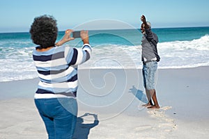 Old couple taking photos at the beach