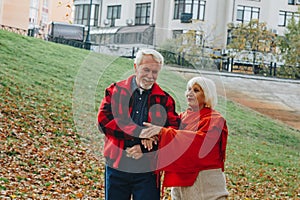 Old couple is walking in the green park. Fifty years together love story. Grandma and grandpa kissing. Grandmother and grandfather