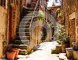 Old courtyard in Pitigliano with vases with flowers and with st