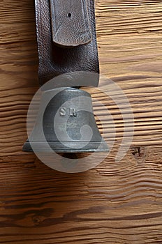 Old cowbell with leather strap on pine wood photo