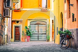 Old cozy street in Trastevere, Rome, Italy with a bicycle and yellow house