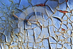 Old cracked blue paint on the desired door, through which rust peeks