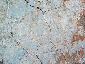 An old cracked brick wall covered with several layers of plaster.