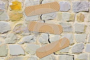 Old cracked and damaged stone wall cause due to subsidence of foundations structural failures - concept with adhesive bandage