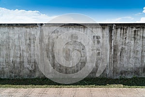 Old cracked gray cement or concrete wall with blue sky as background. Grunge plastered stucco  textured background