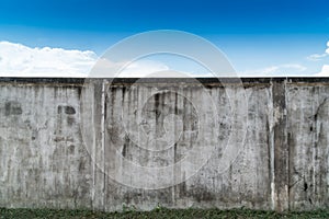 Old cracked gray cement or concrete wall with blue sky as background. Grunge plastered stucco  textured background