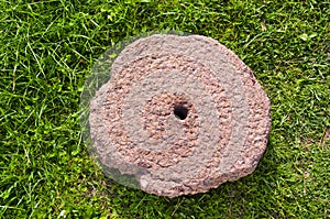 Old cracked millstone on grass