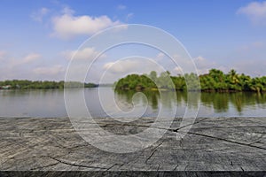 Old cracked wooden table for product display, background of blurred river and tree in Asia, blue sky and clouds, warm light tone