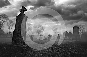 Old creepy graveyard on stormy winter day in black and white