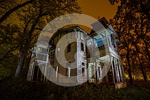 Old creepy wooden abandoned haunted mansion at night