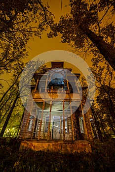 Old creepy wooden abandoned haunted mansion at night