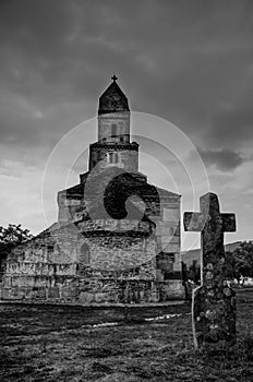 An old cross and Densus medieval church Saint Nicholas, a Dacian and Roman temple in Hunedoara, Hateg, Romania