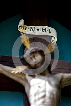 Wooden carved figure of Jesus on the cross, only the inscription INRI in focus