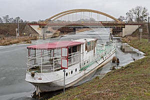 An old cruise ship moored at the airlock on the canal. Abandoned watercraft