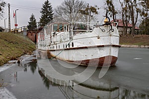 An old cruise ship moored at the airlock on the canal. Abandoned watercraft