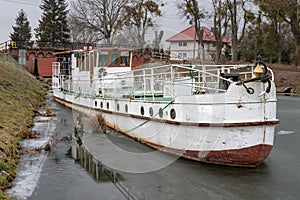 An old cruise ship moored at the airlock on the canal. Abandoned watercraft