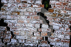 Old crumbling brick wall with gaps through