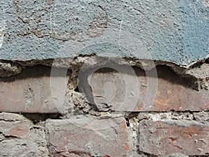 Background texture of old wall with peeling plaster and sticking out of her brick walls.Old red brickwork walls, cement plaster.