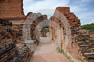 Old crumbling overgrown brick wall in front of stupa at historic park thailand