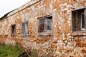 Old crumbling red brick building with small wooden windows