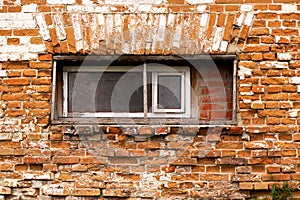 Old crumbling red brick building with small wooden windows