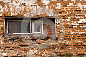 Old crumbling red brick building with small wooden windows