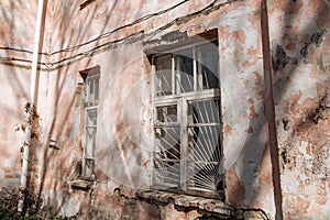 An old, crumbling window with a rusty bars on it. Damaged building