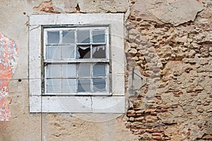 Old crumbly wall with flaking plaster and broken window, abandoned house