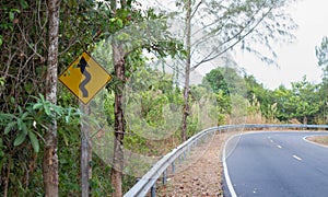 Old curvy road sign beside country road to the forest