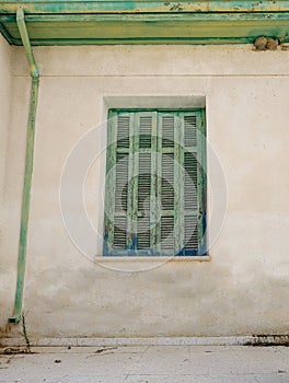 Old Cyprian window with green shutter and drainpipe.