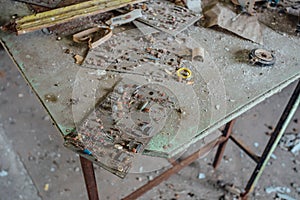 Old damaged dusty soviet electrical circuit boards on the table in abandoned factory of radio components