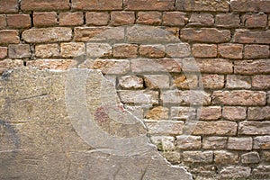 A old damaged red gray brick wall with preserved plaster area. rough surface texture