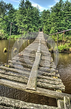 Old and damaged rope and wooden boards bridge over the river Irbe, Latvia photo