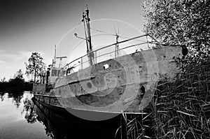 Old and damaged ship on still water
