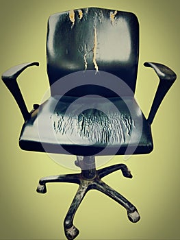 Old damaged used black dirty office chair officechair with rolling casters wheels and torne leather closeup view image photo