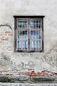 Old damaged wall with window in wooden frame