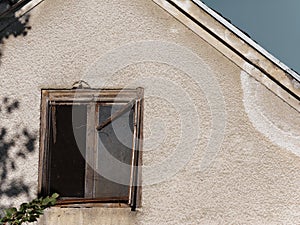 Old damaged weathered wooden window with a wire mesh