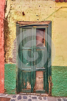 Old damaged wooden door of an abandoned weathered building. Vintage broken and aged green entrance to a house in a small