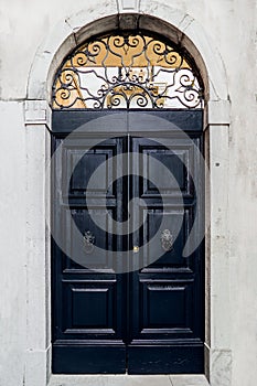 An old dark blue door with handles in the shape of a lion`s head