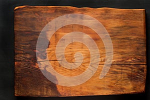 Old dark cutting board on black wooden table, background