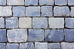Old dark gray cobblestone pavement road from smooth stones as background top view closeup